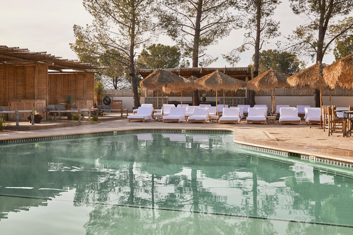 The Ritual Pool at Jacumba Hot Springs Hotel, with white loungers and thatched umbrellas beside mineral water.